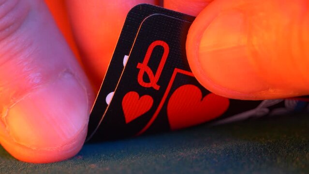 hand holds queen of hearts and jack of clubs in a game of texas hold em poker