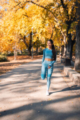 A happy young athletic woman stretching her leg and preparing for a run in the park.