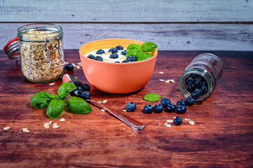 Breakfast table with a bowl of yogurt complemented with blueberries and oatmeal.