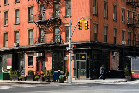 A beautiful corner view of an old building with a classic red brick wall facade and an iron fire escape in New York City