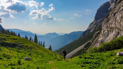 Hiker man on alpine meadow of Hauslalm with panoramic view of Muerztal valley, Hochschwab...