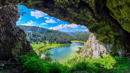 Fototapeta na wymiar Idyllic cave Drachenhoehle with panoramic view of alpine lake Sackwiesensee in Hochschwab mountains, Styria, Austria. Wanderlust in wilderness of Austrian Alps, Europe. Natural arch rock formation