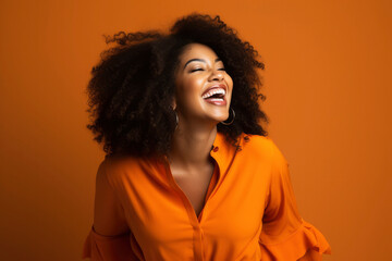 Laughing young pretty African American woman on bright orange background, studio portrait. Happy beautiful dark-skinned girl, concept of human emotions, joy, fun