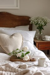 White pillow on the bed with a bouquet of white roses and a cup of coffee