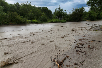 A destroyed road after a flood and mudflow with flowing dirty water. Natural disasters concept.
