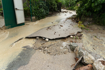 A destroyed road after a flood and mudflow with flowing dirty water. Natural disasters concept.
