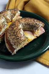 Sandwich of bologna with mustard on a poppy seed bagel.