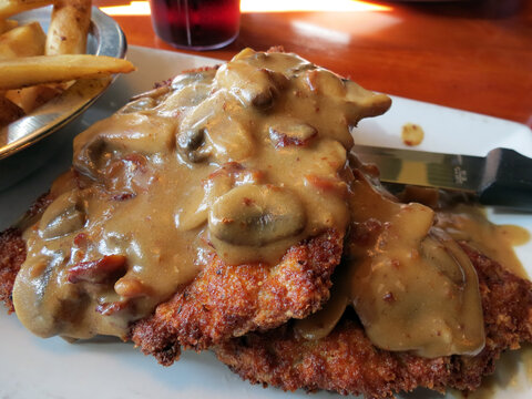 Pork schnitzel with mushroom gravy, served with French fries