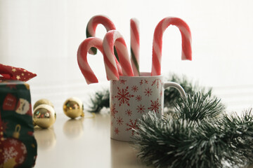 Traditional christmas decoration, colorful candy canes and cones in the white and red cup on white wooden background, High quality photo