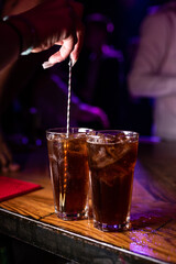 The bartender stirs the finished cocktails with a bartender's spoon. Mixing an alcoholic cocktail in a nightclub, pub, restaurant