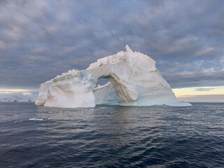 A huge high breakaway glacier drifts in the southern ocean off the coast of Antarctica at sunset,...