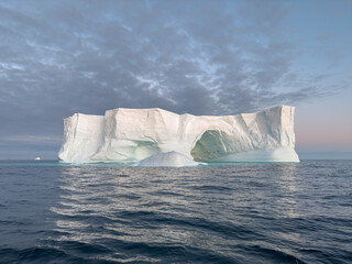 A huge high breakaway glacier drifts in the southern ocean off the coast of Antarctica at sunset,...