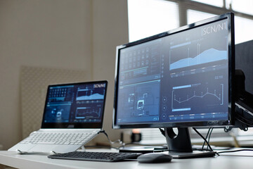 Close up background image of computers on desk in cybersecurity office with data screens reflecting light copy space