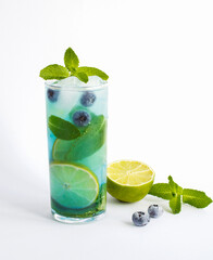 Cold drink with lime, blueberry and mint in the drinking glass on the white background. Copy space.