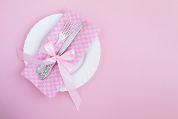 Table setting with pink napkin in the pink background. Top view. Copy space.