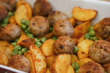 Delicious hot lunch from the oven potato slices, meatballs and green peas