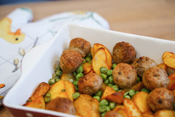 Fototapeta premium Delicious hot lunch from the oven potato slices, meatballs and green peas