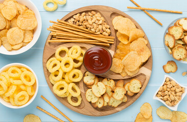 Various unhealthy snacks on wooden background, top view