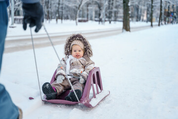 Child toddler on a sled in a snowy winter forest