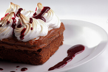 Brownie cake with merengue and cream and chocolate syrup