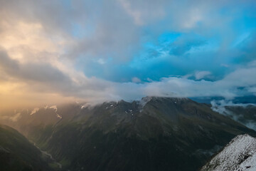 Panoramic view from mountain peak Arnoldhoehe in Ankogel Group, High Tauern National Park, Austria. Wanderlust in untamed snow covered Austrian Alps. Cloud covered terrain in idyllic hiking atmosphere