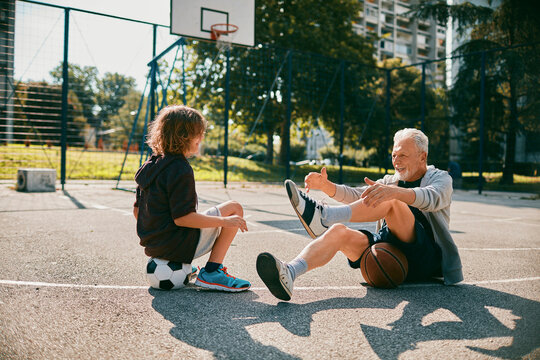 Grandfather and grandson with soccer and basketball on an outdoor court