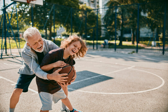 Grandfather and grandson bonding over basketball in a park