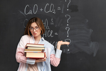 A student tired of complex chemistry stands near the blackboard and tries to understand chemical reactions