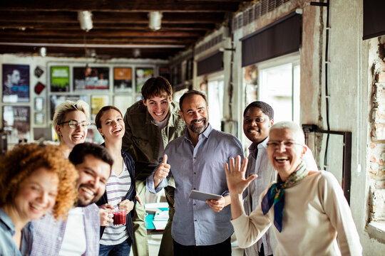 Diverse and multigenerational group of people looking at the camera while working in a startup company office