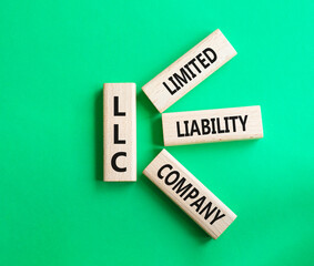 LLC - Limited liability company. Wooden cubes with word LLC. Beautiful green background. Business and LLC concept. Copy space.