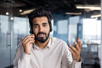 Young indian businessman in office environment communicating over headset