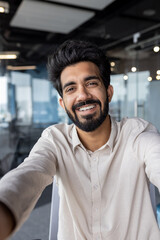 Obraz premium Smiling indian businessman in casual shirt at modern office space