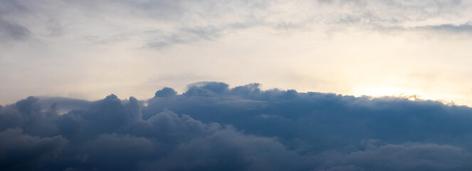 A dark storm cloud at the bottom of the evening sunlit sky