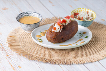 Corviche de verde relleno de pescado en su interior con ensalada de tomate y cebolla y salsas, bocado típico ecuatoriano