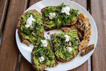 Smashed avocado on Toast with Labneh, Lemon, Parsley, Cheese, Edamame and different dried seeds, sunflower and pumpkin, very healthy and vegan green breakfast made by organic ingredients, healthy food