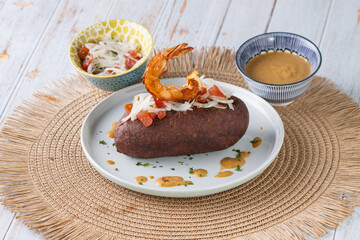 Corviche de verde relleno de camaron en su interior con ensalada de tomate y cebolla y salsas, bocado típico ecuatoriano