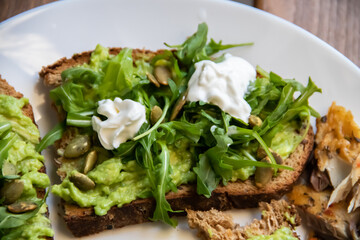 Smashed avocado on Toast with Labneh, Lemon, Parsley, Cheese, Edamame and different dried seeds, sunflower and pumpkin, very healthy and vegan green breakfast made by organic ingredients, healthy food