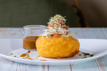 Papa rellena de carne con salsa de carne adornada con tomate, cebolla, aperitivo ecuatoriano