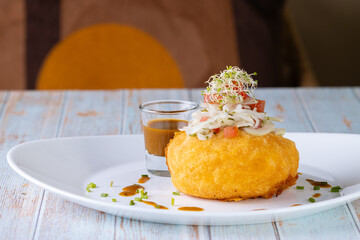 Papa rellena de carne con salsa de carne adornada con tomate, cebolla, aperitivo ecuatoriano