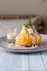 Papa rellena de camarón con salsa agria adornada con tomate, cebolla y camarones, aperitivo...
