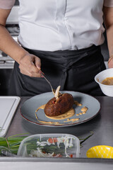 Chef Mujer adulta estilizando un corviche de cangrejo para servir al comensal