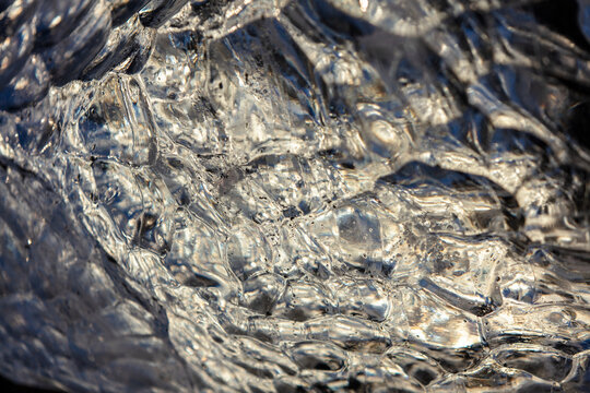 Backlit detail of a frozen glacial ice fragment with golden bubble pattern in Iceland