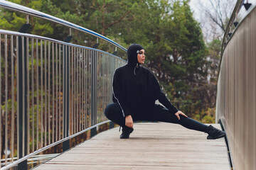 Hijab girl exercising on walkway bridge in early morning. Muslim woman wearing sports clothes doing stretching workout outdoors.
