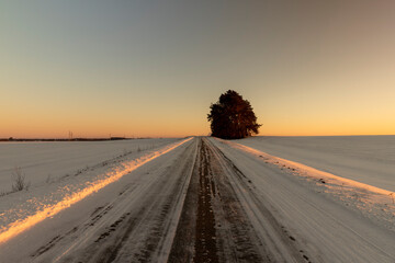 slippery and dangerous road covered with snow and ice at sunset - obrazy, fototapety, plakaty