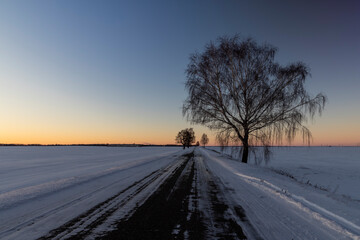 a slippery and dangerous road covered with snow and ice at sunset