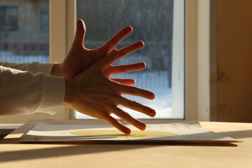 Young man hands and contrasting sunlight on a window background. Photo was taken 22 January 2024...