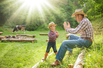 happy child with cowboy parent in nature in the field