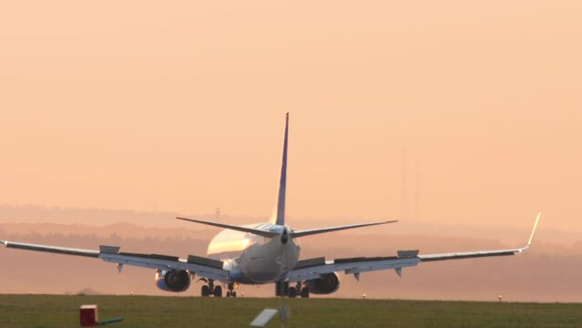 Passengers airplane landing to airport runway in beautiful sunset light, mileage and braking speed reduction