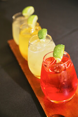 Vibrant Trio of Citrus Garnished Cocktails on Rustic Wood Board