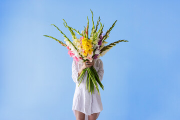 girl with gladioli flowers in white clothes on a white background